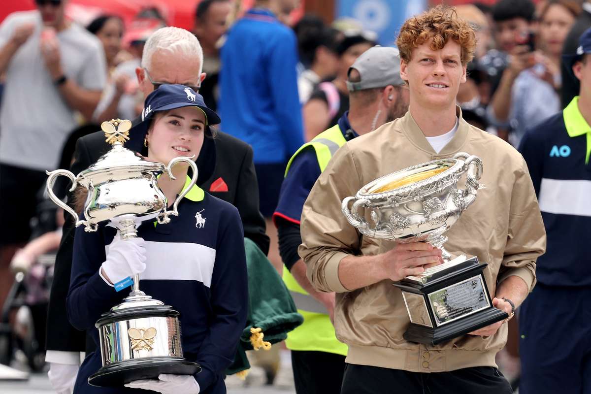 Jannik Sinner and ball girl Peyton Billington carry the singles trophies through Melbourne Park prior to Thursday's draw.