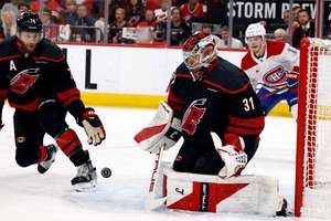 The puck bounces between Carolina Hurricanes goaltender Frederik Andersen and Jaccob Slavin with Montreal Canadiens' Cole Caufield (13) nearby