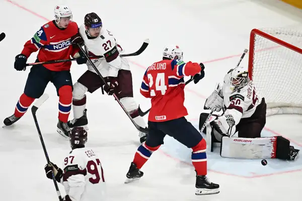 Latvia's goalkeeper Kristers Gudlevskis (R), Latvia's defender Oskars Cibulskis (2L) and Latvia's forward Haralds Egle vie for the puck