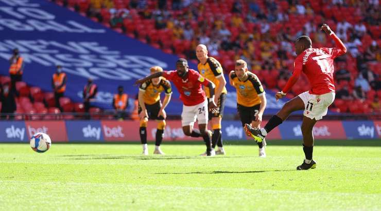Vào! Carlos Mendes Gomes (Morecambe) giành chiến thắng trên chấm phạt đền bằng một cú sút không thể cản phá, vượt qua tầm với của thủ môn Tom King vào góc thấp bên trái.