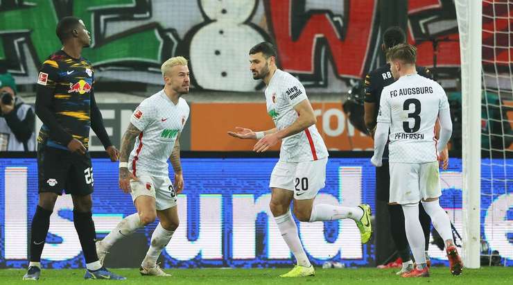 Vào! Daniel Caligiuri (Augsburg) giành chiến thắng trên chấm phạt đền bằng một cú sút không thể cản phá, vượt qua tầm với của thủ môn Peter Gulacsi vào góc trái khung thành.