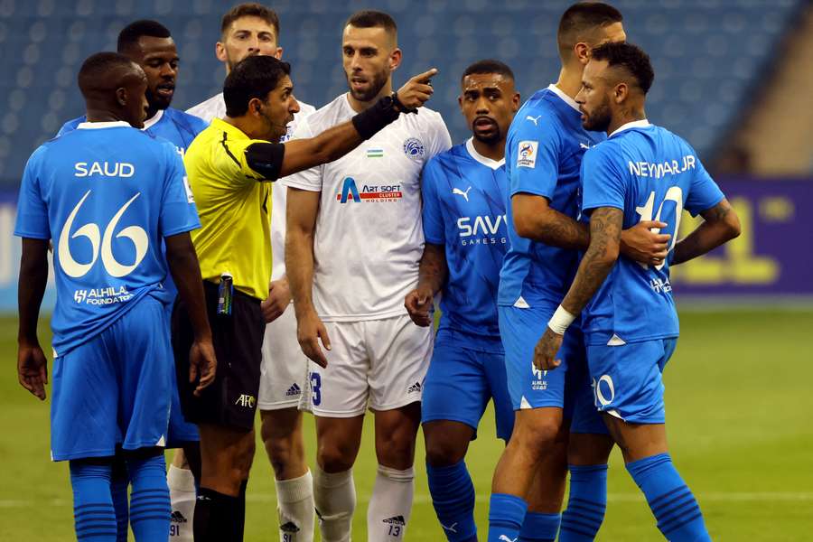 The referee gestures to Al-Hilal forward Neymar