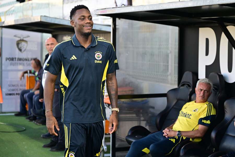 Fenerbahce's new signing Jhon Duran smiles as he walks past the bench, while head coach Jose Mourinho looks on