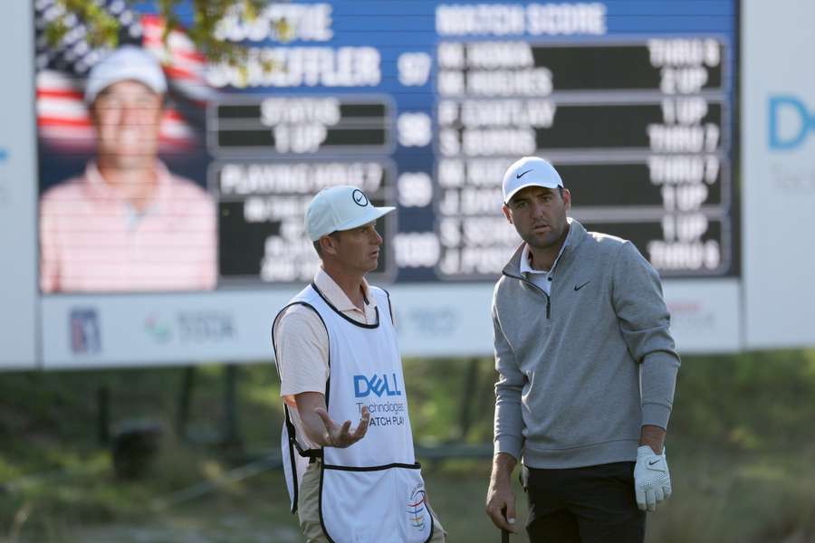 Scottie Scheffler of the United States and his caddie line up a shot on the seventh hole 