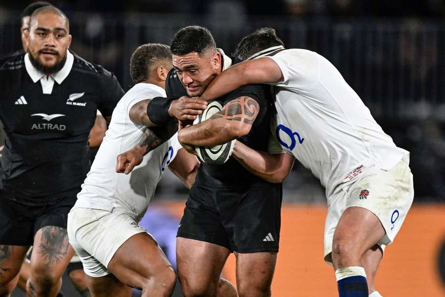 New Zealand's Codie Taylor, second right, is tackled by England defenders 