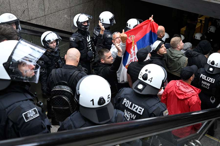De politie begeleidt Servische fans, die om onduidelijke redenen bepaalde vingers opsteken