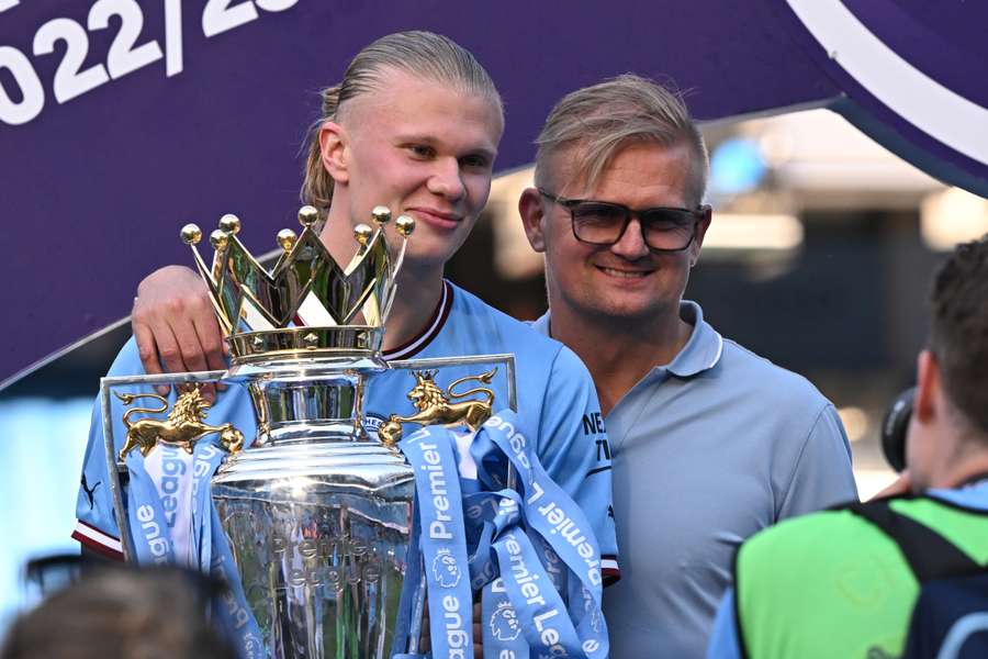 Erling Haaland (esq.), atacante norueguês do Manchester City, e seu pai Alf-Inge Haaland (dir.) posam com o troféu da Premier League