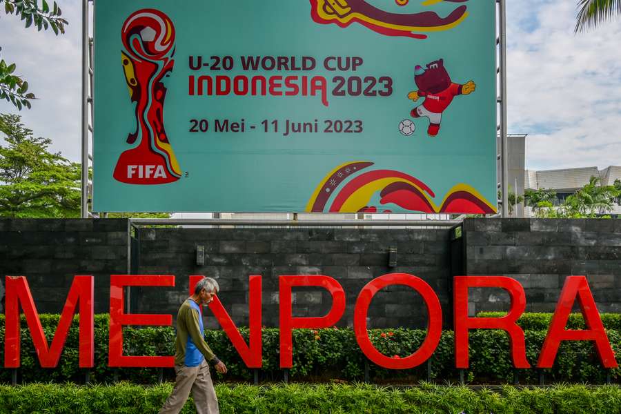 A man walks past a poster for the Indonesia 2023 FIFA Under-20 World Cup