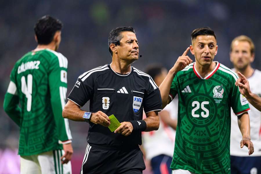 Referee Alireza Faghani shows a yellow card during the match between Mexico and England. 