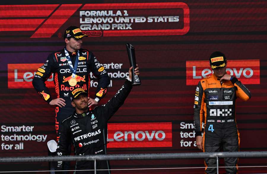 Red Bull Racing's Dutch driver Max Verstappen, Mercedes' British driver Lewis Hamilton, and McLaren's British driver Lando Norris listen to the national anthems on the podium