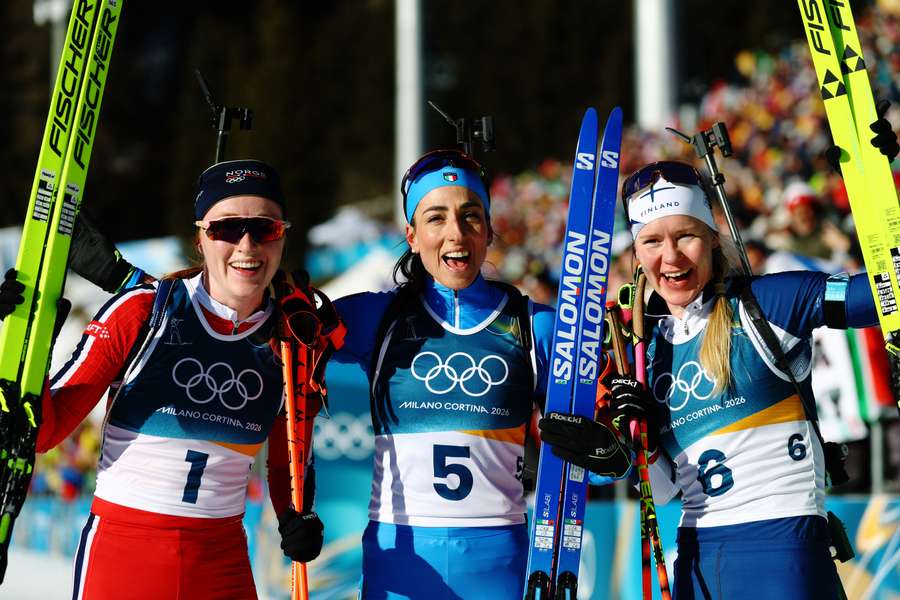 Lisa Vittozzi celebrates after winning the women's 10km pursuit alongside silver medalist Maren Kirkeeide and bronze medallist Suvi Minkkinen