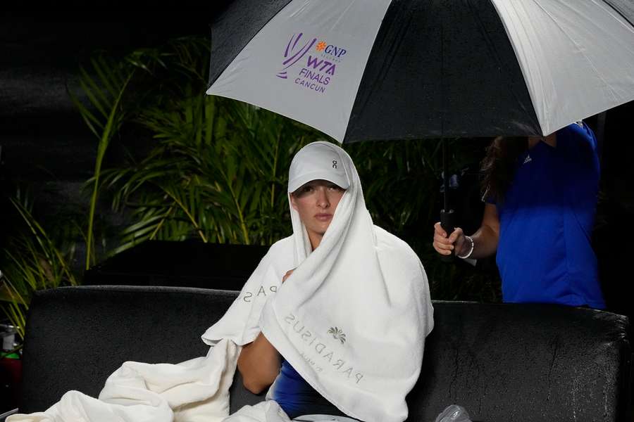 Iga Šwiateková se během semifinálového utkání schovávala před deštěm.