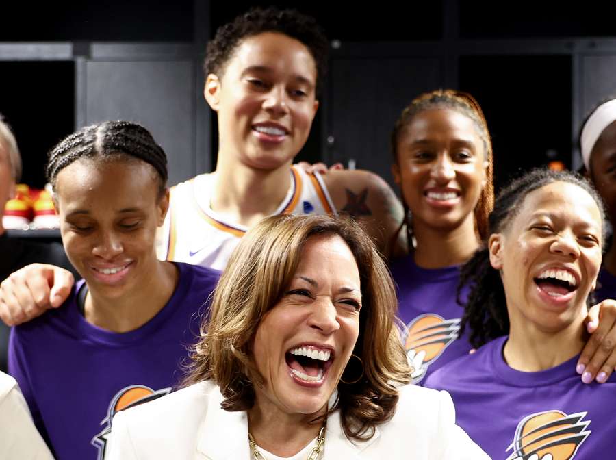 Vice President Kamala Harris (C) laughs while standing with Brittney Griner (TOP) and other members of the Phoenix Mercury in the locker room