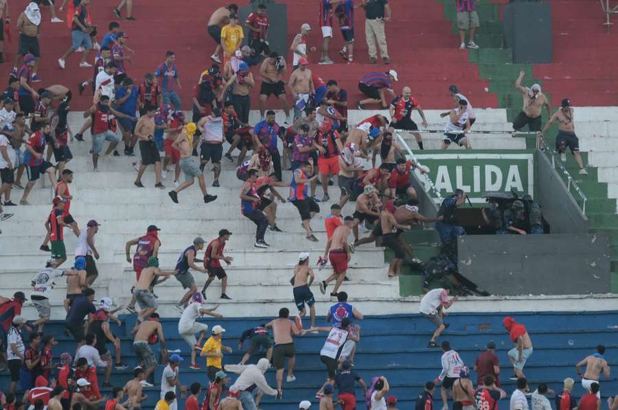 Fans of Cerro Porteno clash with police officers during the Paraguayan tournament football match between Olimpia and Cerro Porteno