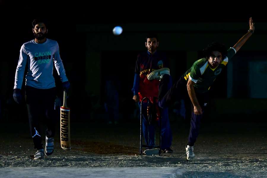 In this picture taken on April 7, 2023, cricketer Owais Afridi (R) delivers a ball during the tape ball night cricket tournament