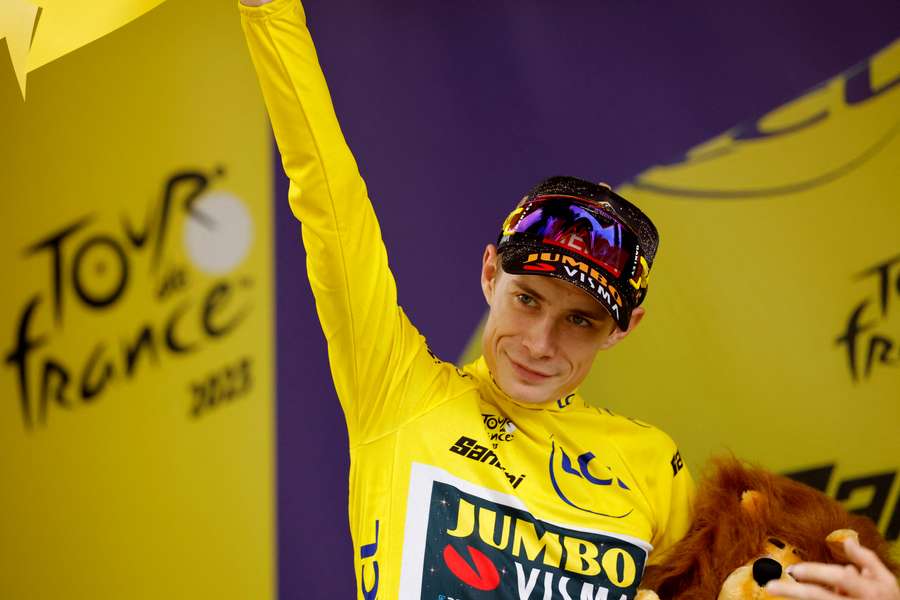 Jonas Vingegaard celebrates on the podium wearing the yellow jersey after stage 19
