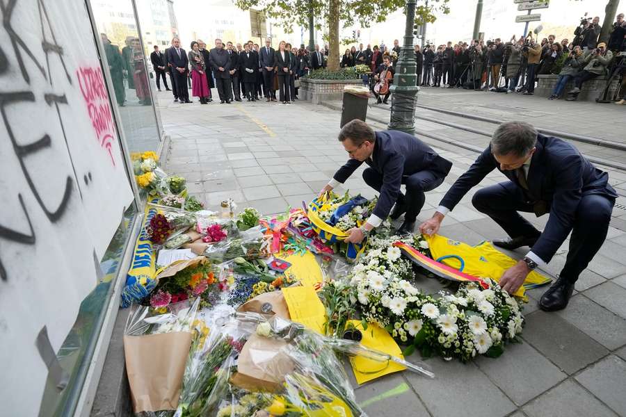 Ulf Kristersson (L) en Alexander De Croo leggen een sjaal en shirt bij de locatie van de aanslag in Brussel