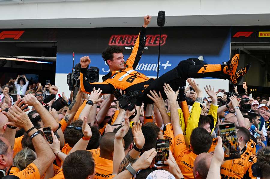 Vítězný Lando Norris nad hlavami členů McLarenu.