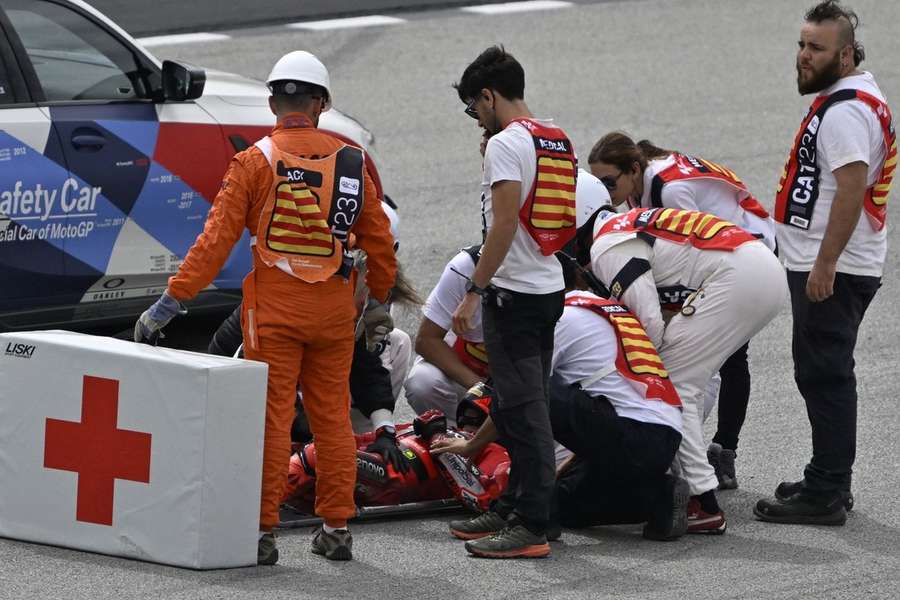 Bagnaia wordt geholpen door de medische staf na zijn crash