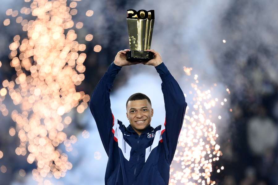 Kylian Mbappe raises a trophy during a ceremony after he became Paris Saint-Germain's all-time top scorer