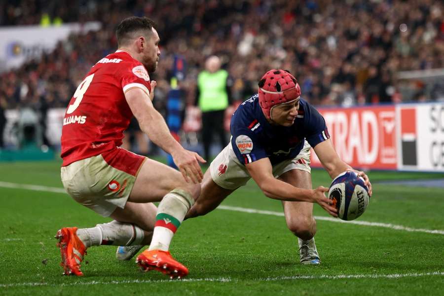 France's left wing Louis Bielle-Biarrey (R) dives over the line to score France's fourth try in front of Wales' scrum-half Tomos Williams (L) 