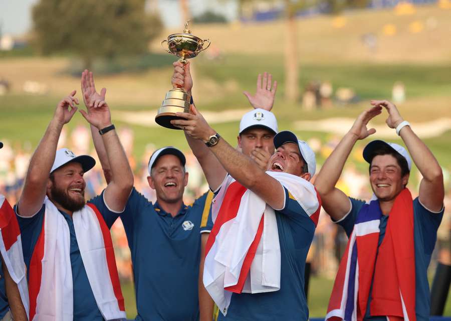 McIlroy celebrates with the trophy and teammates during the presentation after winning the Ryder Cup