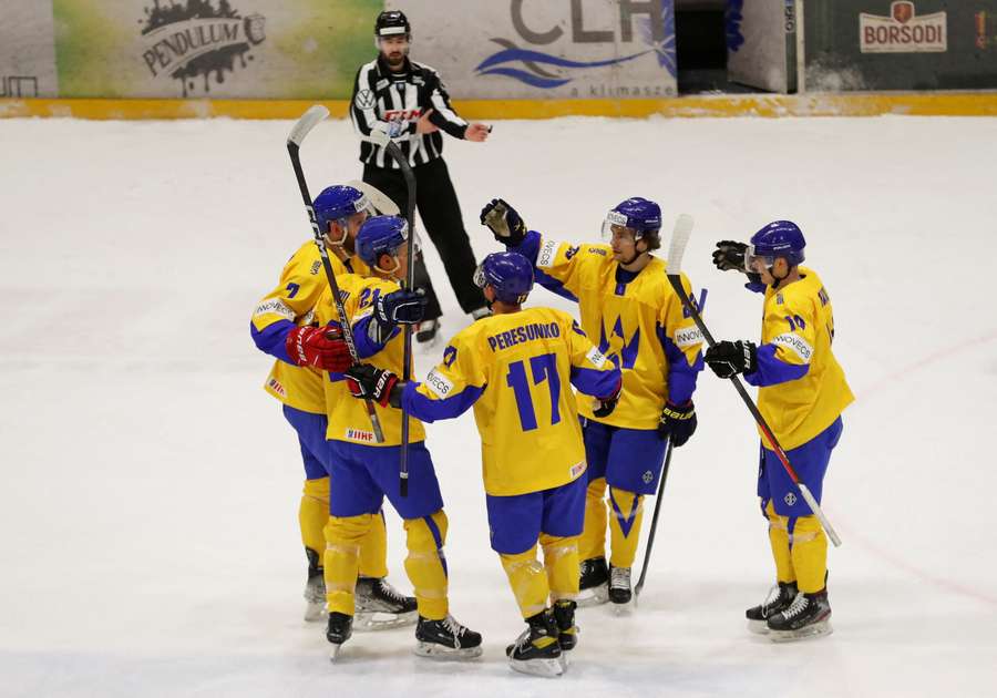 Leden van het Oekraïense mannen ijshockeyteam vieren hun doelpunt tegen Hongarije