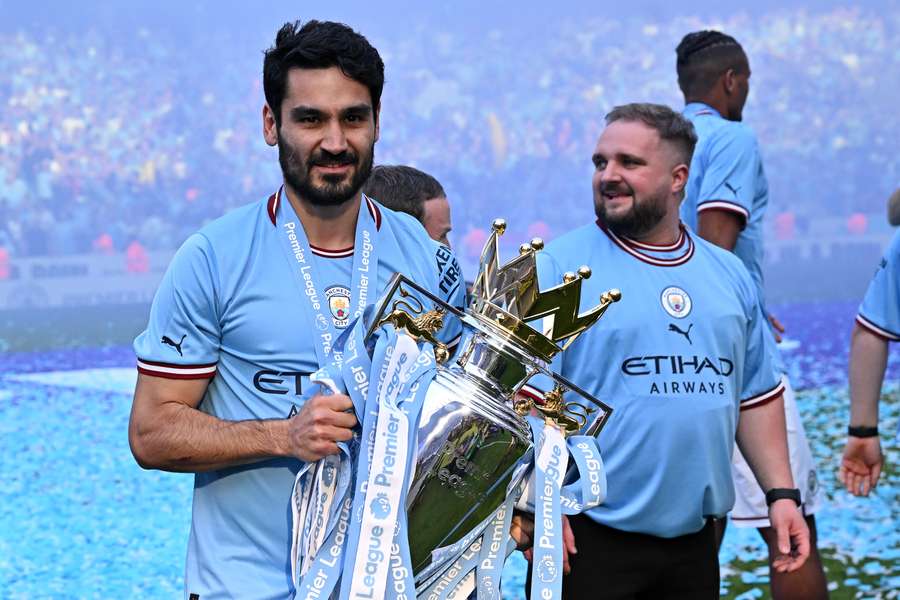 O meio-campista alemão do Manchester City, Ilkay Gundogan, posa com o troféu da Premier League no gramado