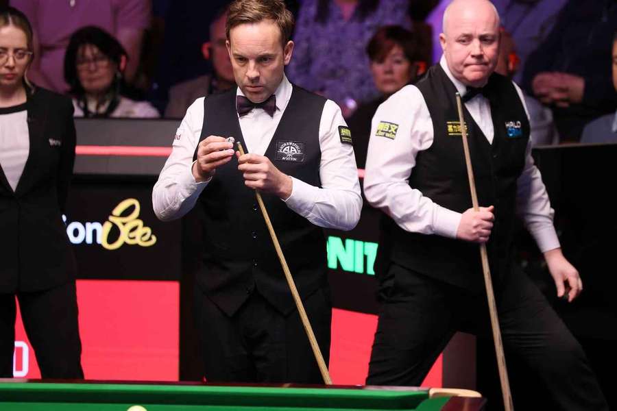 Ali Carter (l.) am Tisch, während John Higgins (r.) Platz machen muss.