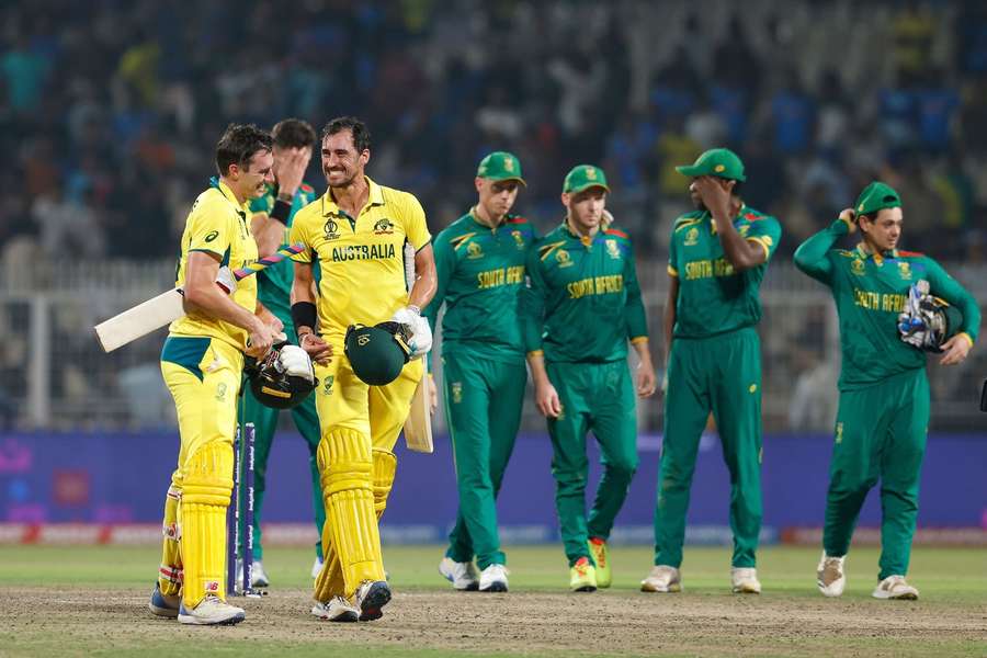 Australia's players celebrate winning the game with South Africa's players in the background