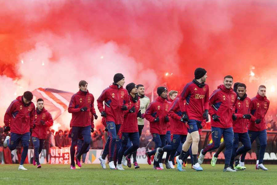 De spelers van Ajax trainen met in hun rug een grote schare fans met fakkels