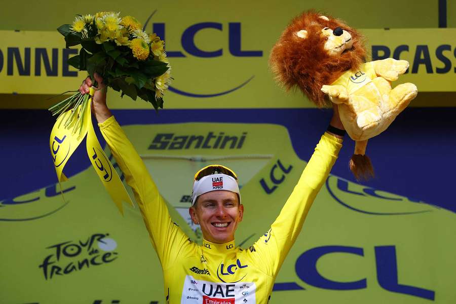 Tadej Pogacar celebrates on the podium wearing the yellow jersey after stage 15 of the Tour de France