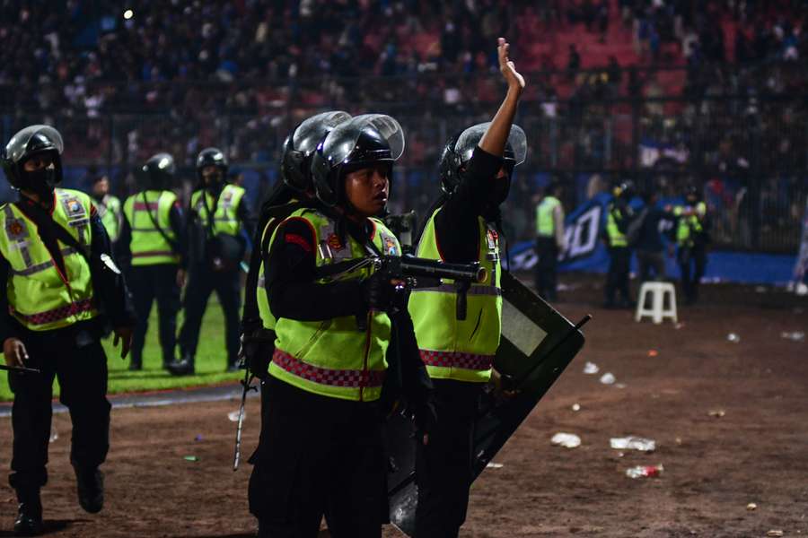 Police holding tear gas guns and gesturing at the crowd after a football match between Arema FC and Persebaya at the Kanjuruhan stadium in Malang, East Java.