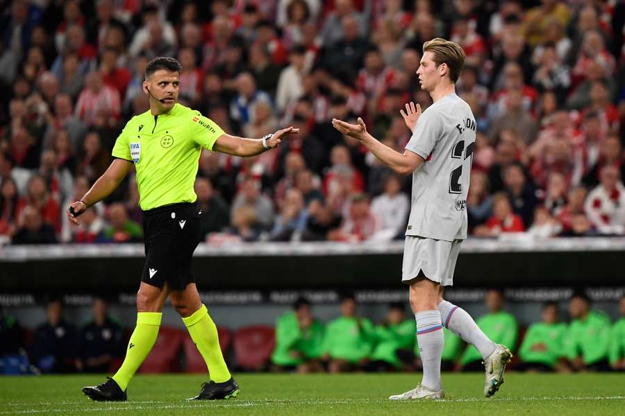 Referee Gil Manzano talks to Barcelona midfielder Frenkie de Jong.