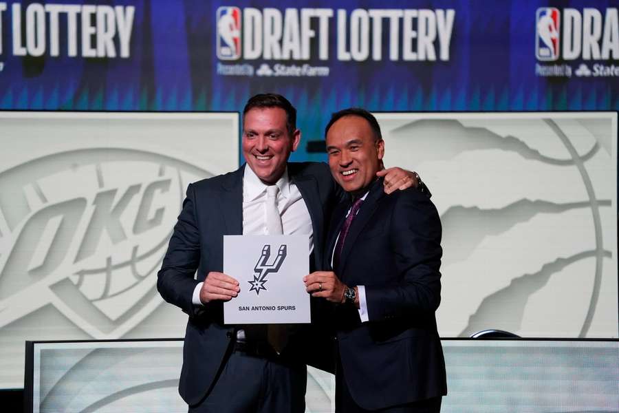 NBA Deputy Commissioner Mark Tatum (rechts) feliciteert Spurs' managing partner Peter J. Holt (links) met de top pick