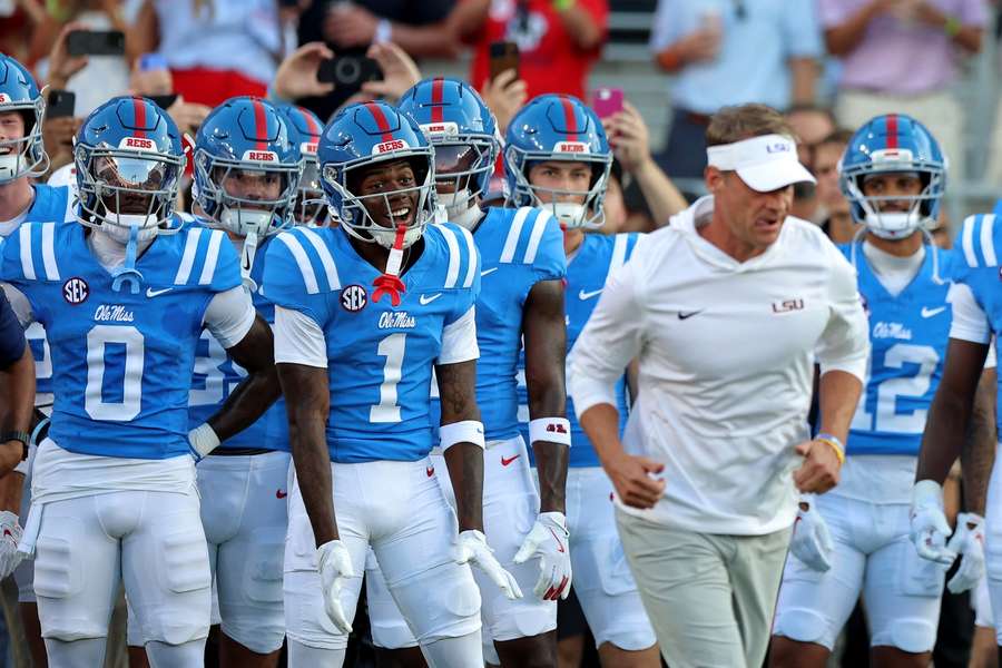 Ole Miss players reacting behind their former head coach Lane Kiffin