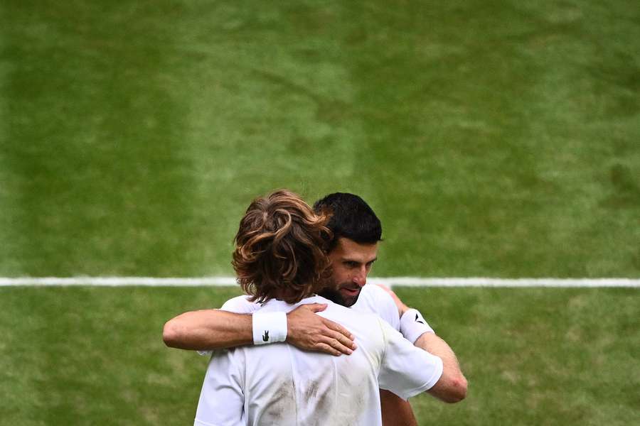 Serbia's Novak Djokovic (rear) hugs Russia's Andrey Rublev after winning their men's singles quarter-finals tennis match