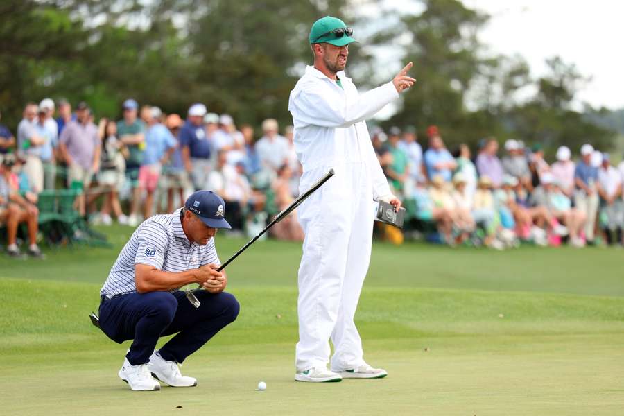 Bryson DeChambeau of the United States lines up a putt with his caddie