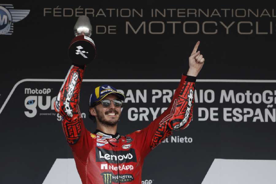 Francesco Bagnaia celebrates with the trophy on the podium after winning the race