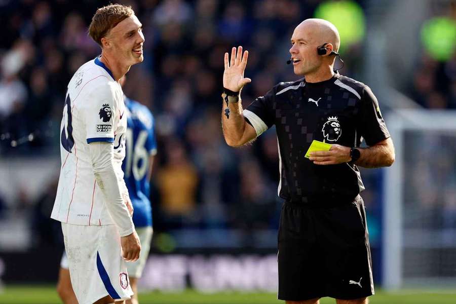 Referee Paul Tierney has words with Chelsea's Cole Palmer and shows him a yellow card