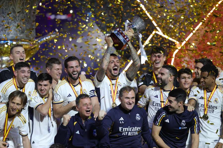 Real Madrid's Spanish forward #14 Joselu lifts the trophy as he celebrates with his teammates after winning the Spanish Super Cup