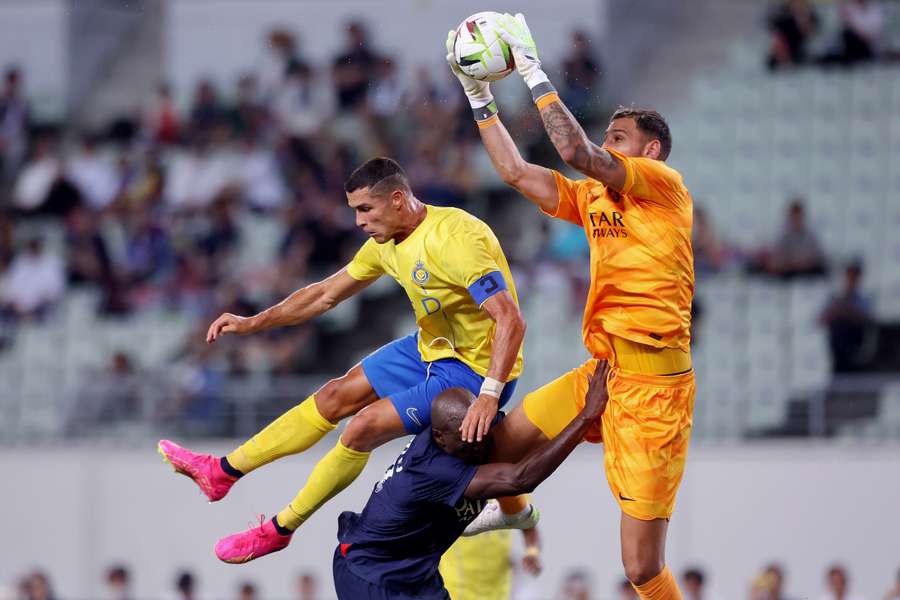 Al-Nassr's Cristiano Ronaldo (L) fights for the ball with Paris Saint-Germain's Gianluigi Donnarumma (R) and Danilo Pereira (bottom)