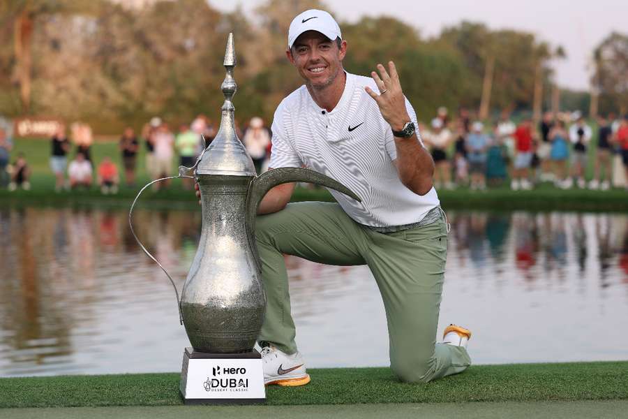 Rory McIlroy of Northern Ireland poses with the trophy and signals his fourth victory