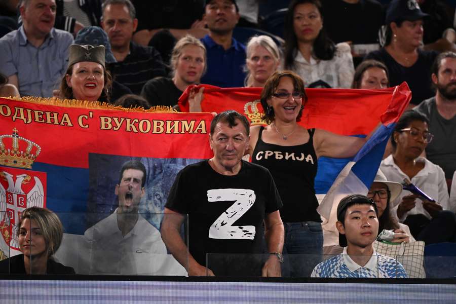 A man wearing a 'Z' shirt watches the men's singles quarter-final match between Serbia's Novak Djokovic and Russia's Andrey Ruble, next to supporters holding up Serbian flags