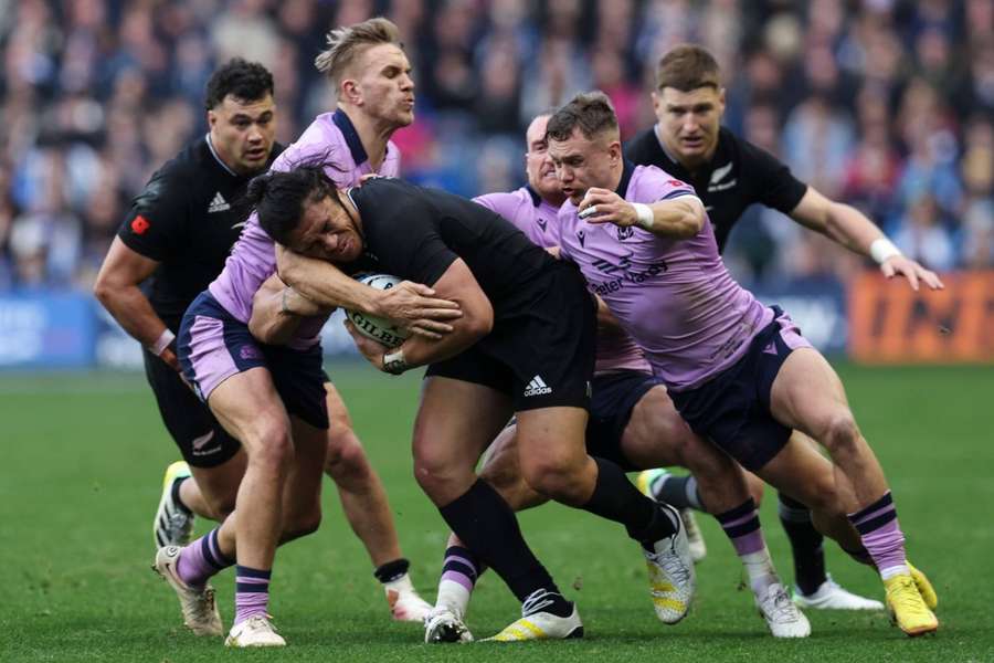 Caleb Clarke of New Zealand is tackled by Scotland's Darcy Graham and Chris Harris.