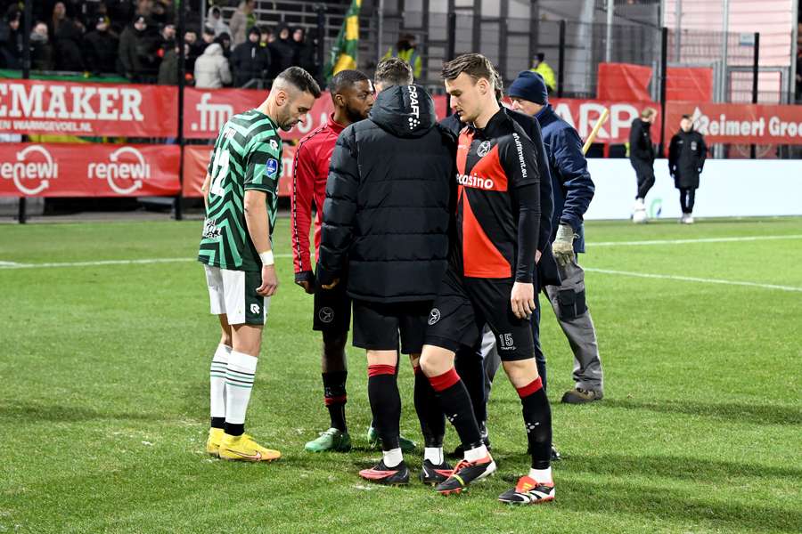 Spelers van beide ploegen inspecteren het veld