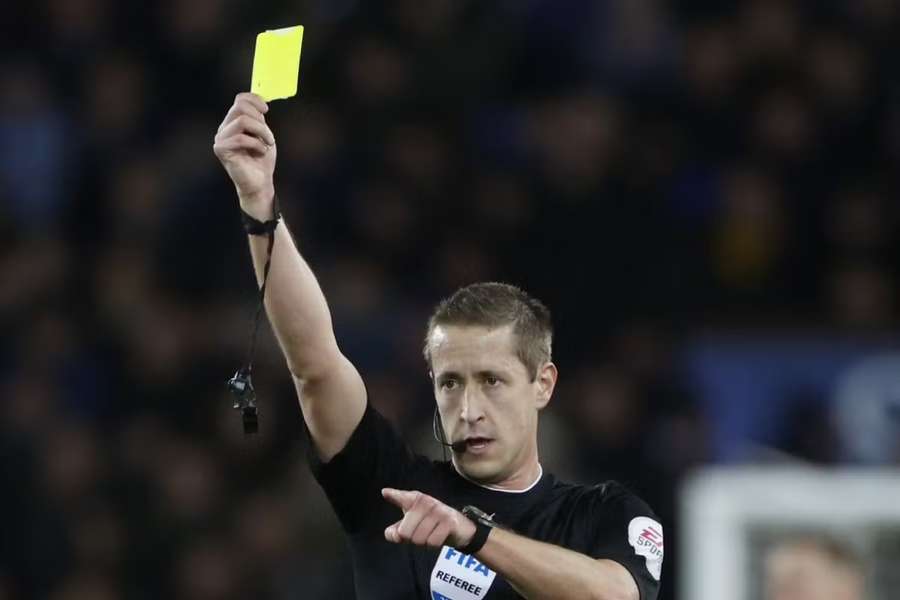 Referee John Brooks shows a yellow card