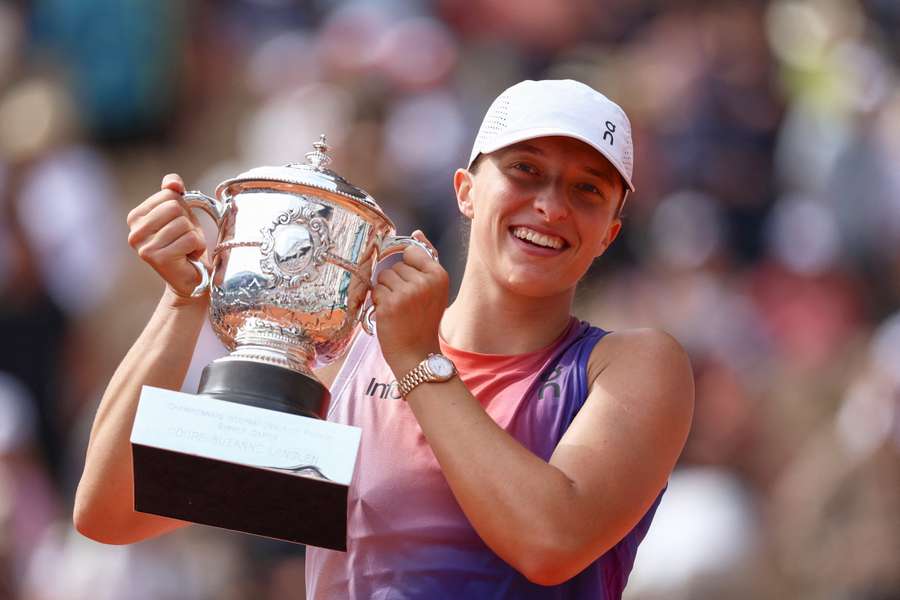 Iga Swiatek celebrates with the trophy after winning against Jasmine Paolini