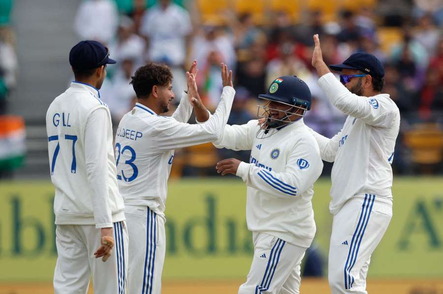 India's Kuldeep Yadav celebrates with Rohit Sharma and teammates after taking the wicket of England's Ollie Pope