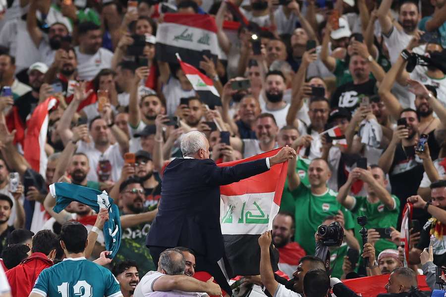 Graham Arnold unfurls an Iraqi flag to supporters in Mexico after securing 2026 FIFA World Cup qualification.